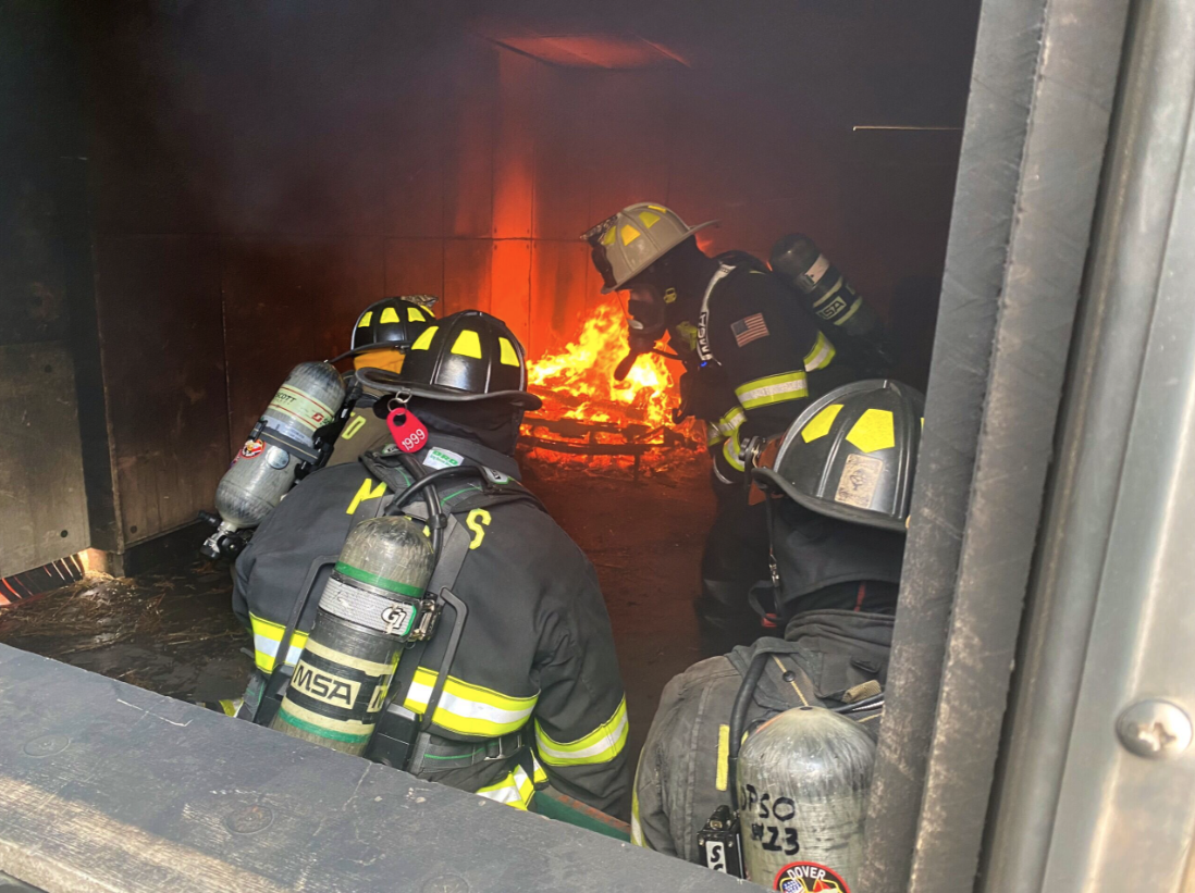 Interior fire training scene with firefighters advancing toward fire
